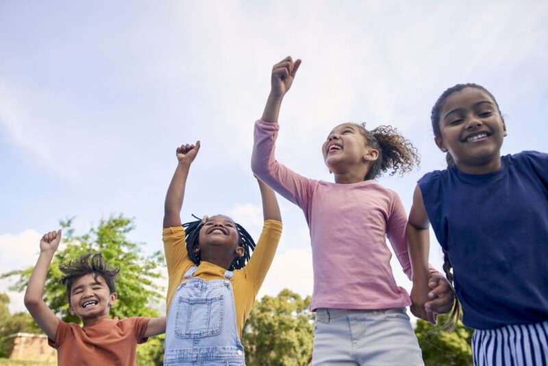 Picture Writing Prompts: Cheering Children, energy and diversity with friends cheering together outdoor while having fun during the day. Kids, freedom or celebration with a girl and boy group playing or bonding outside in summer